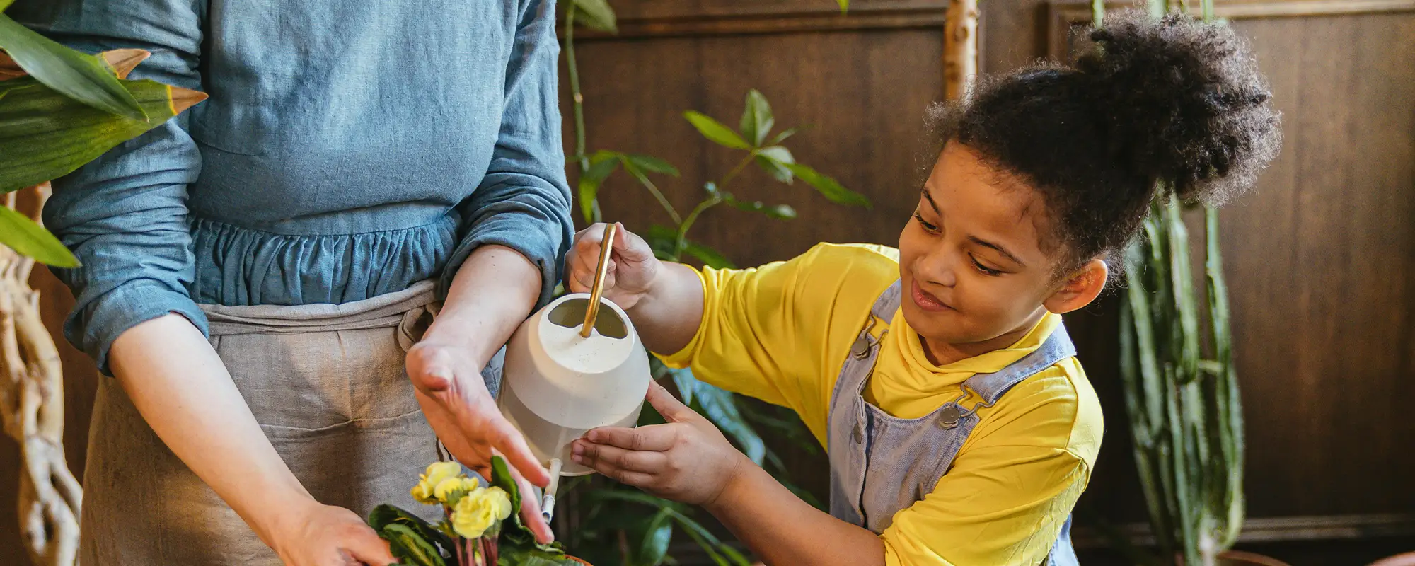 mother helping daughter pour water on plants