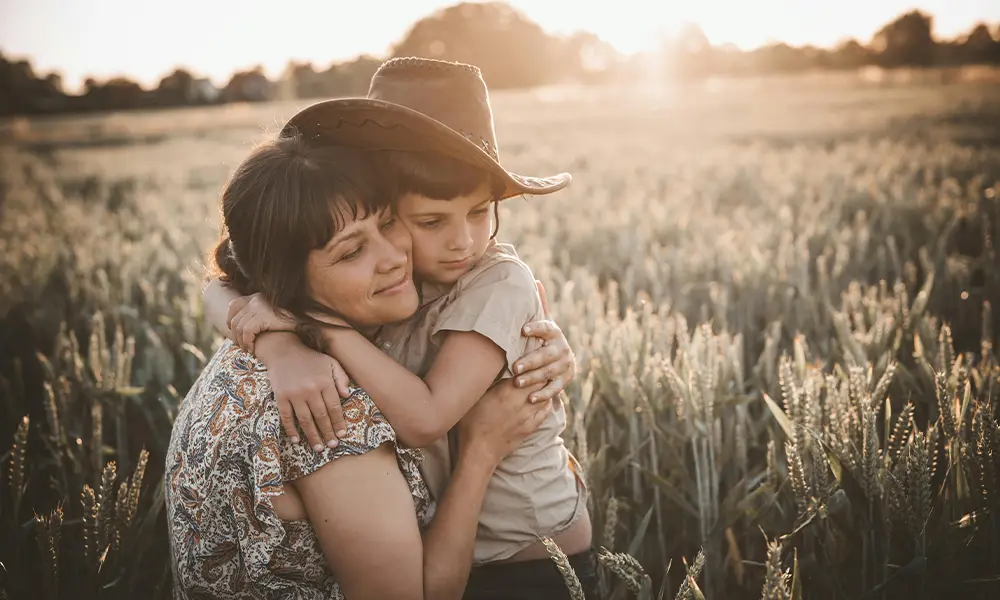 mother holding son who wears cowboy hat